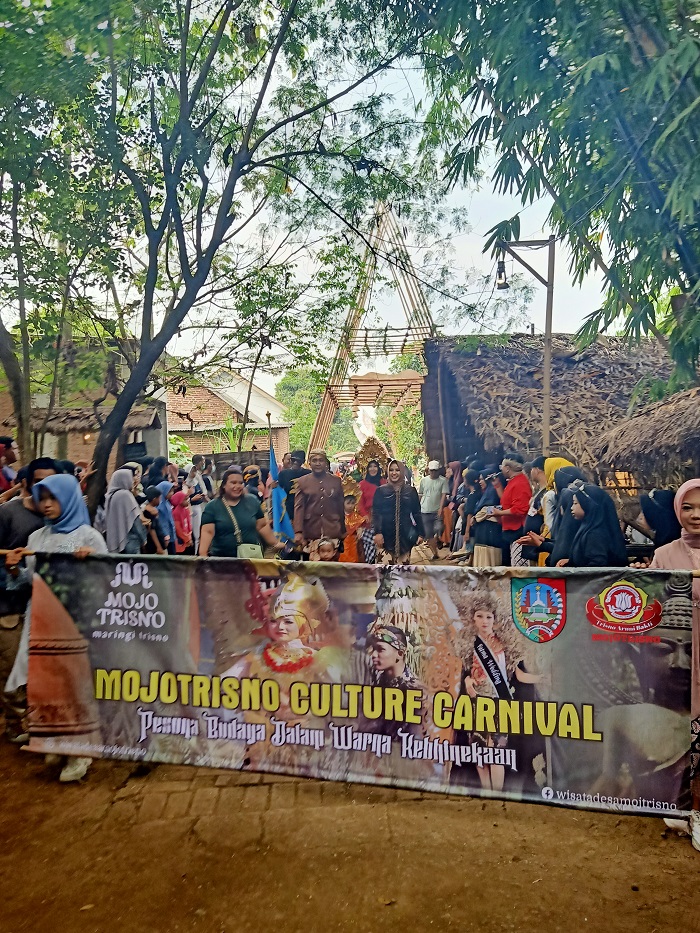 SEMARAK: Kepala Desa Mojotrisno Nanang Sugiarto menyaksikan tumpeng hasil bumi dan jajan tradisional yang diperebutkan oleh warga dan para pengunjung.