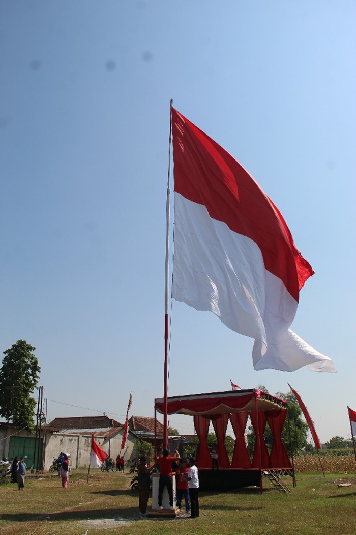 BERKIBAR: Ratusan warga Desa Ngudirejo, Kecamatan Diwek saat mengirab bendera jumbo ukuran 10x15 meter, Sabtu (17/8).