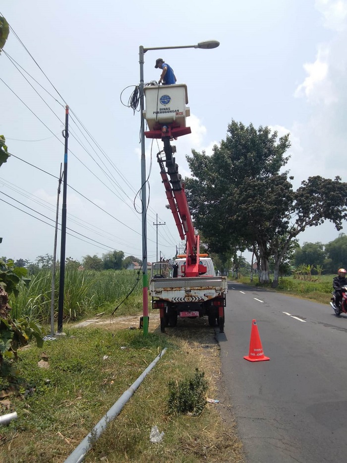 RESPONSIF: Petugas perbaikan PJU dari Dishub Jombang sedang memperbaiki kerusakan pada penerangan jalan.