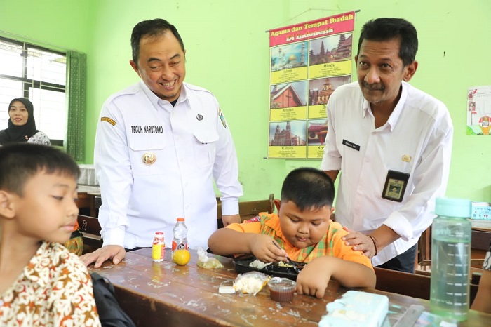 CEGAH GIZI BURUK: Kepala Desa Kepatihan Erwin Pribadi mendampingi Pj Bupati Jombang Teguh Narutomo saat meninjau simulasi program makan siang gratis di SDN Kepatihan.