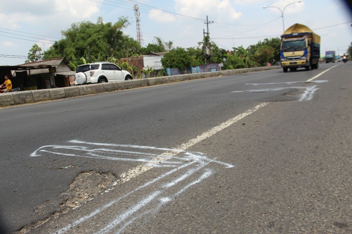 HATI-HATI: Pengendara saat melintas di jalan nasional yang rusak dan ditandai dengan cat di Desa Jogoloyo Kecamatan Sumobito, Jombang, (23/10).