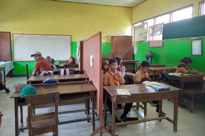 SEMANGAT: Siswa SDN Kepuhkembeng 3 Kecamatan Peterongan, Jombang belajar dengan berbagi ruang kelas dengan sekat papan kayu.