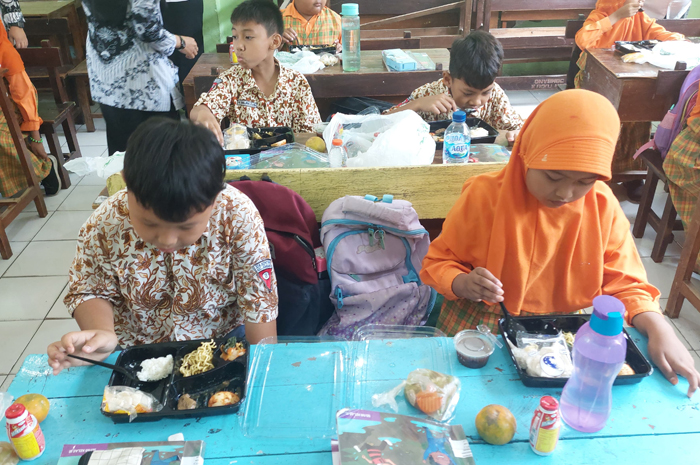 SENANG:  Siswa SDN Kepatihan Jombang menikmati uji coba makan siang gratis, Rabu (25/9).