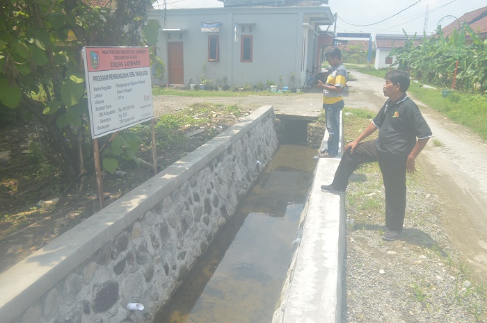 ATASI GENANGAN: Kades Losari, Ploso, Jombang, Sutrisno (kaos hitam) menunjukkan saluran drainase baru saja selesai dibangun.