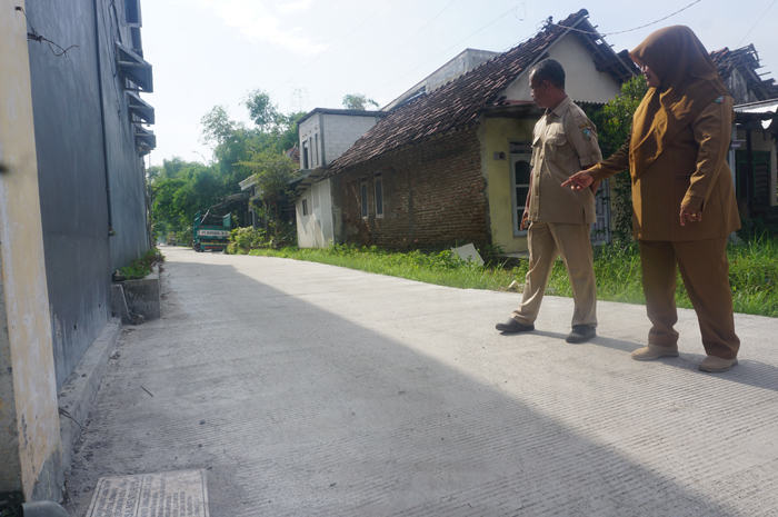 SEMAKIN BERKEMBANG: Kepala Desa Menturus Nyamiati didampingi perangkat saat menunjukkan salah satu lokasi pembangunan jalan rabat beton di Dusun/Desa Menturus