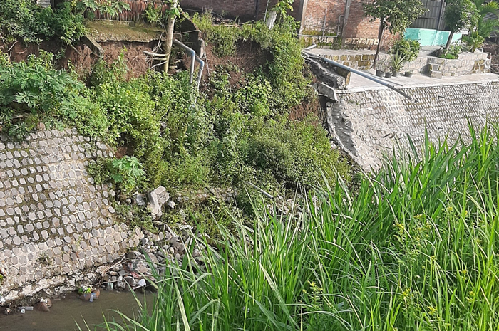 Kondisi tanggul sungai yang longsor dan mengancam rumah warga di Mojowarno, Jombang