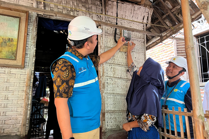 SELAMAT: Manajer PLN UP3 Mojokerto Muhammad Syafdinuur bersama penerima bantuan secara simbolis menyalakan meteran listrik bantuan listrik gratis di Jombang.