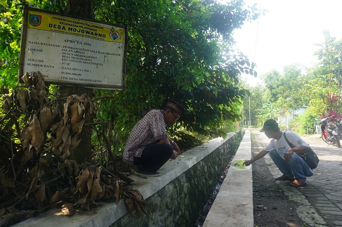 ATASI BANJIR: Kepala Desa Mojowarno Tatag Yudianto (kiri) didampingi Ketua TPK Desa Mojowarno Erwanto saat menunjukkan lokasi pembangunan saluran drainase beton bertulang di Dusun Mojowarno 1.
