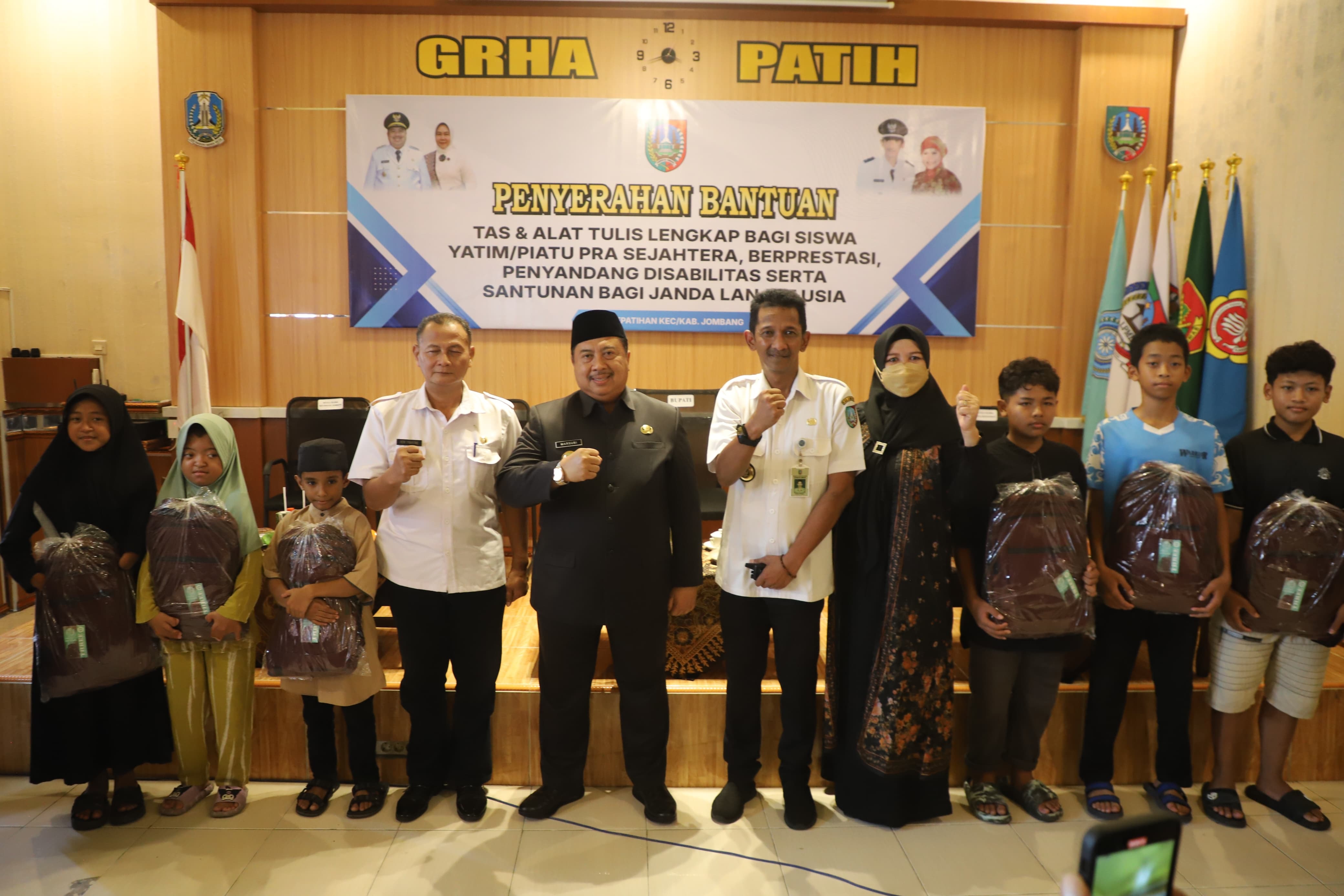 PEDULI: Bupati Jombang Warsubi mendampingi Erwin Pribadi Kades Kepatihan saat menyalurkan bantuan tas dan alat tulis sekolah, Rabu (28/5).