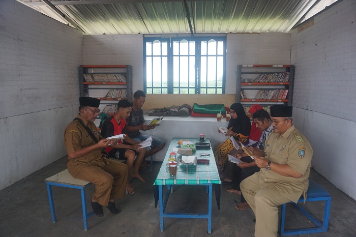 SEMANGAT LITERASI: Kepala Desa Keras Sukardi dan Camat Diwek Agus Sholihudin membaur bersama warga setempat saat membaca buku di perpustakaan Desa Keras.