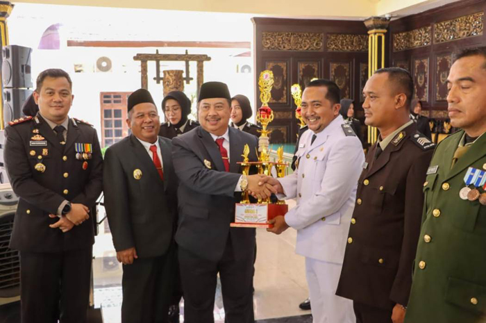 KOMITMEN KEAMANAN: Kepala Desa Mojotrisno Nanang Sugiarto menerima piala penghargaan juara 1 Kapolres Award Desa Aman 2025 dari Bupati Jombang Warsubi di pendopo Kabupaten Jombang, Selasa (1/7) pagi.