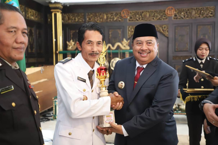 KOMITMEN KEAMANAN: Kades Mentoro Mahfudz Efendi saat menerima piala penghargaan juara Harapan 1 Kapolres Award Desa Aman 2025 dari Bupati Jombang Warsubi di pendopo Kabupaten Jombang, Selasa (1/7).