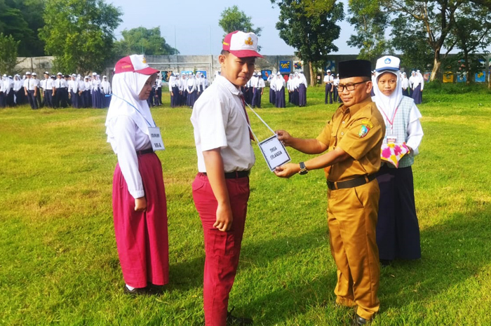 PEMBUKAAN: Kepala SMPN 2 Peterongan, Jombang, Drs Sarmin, menyematkan identitas saat upacara pembukaan MPLS (14/7).