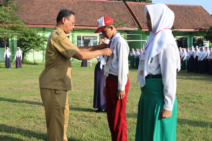 PANUTAN: Kepala SMPN 1 Gudo, Jombang, Imam Suhardi MMPd menyematkan tanda peserta MPLS kepada siswa baru (14/7).