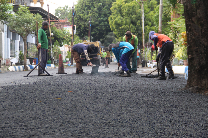 MAKIN MULUS: Tim mandor jalan Dinas PUPR Jombang saat melakukan perbaikan jalan di Jl Dr Setiabudi, Jombang (9/7). (Anggi Fridianto/Radar Jombang)