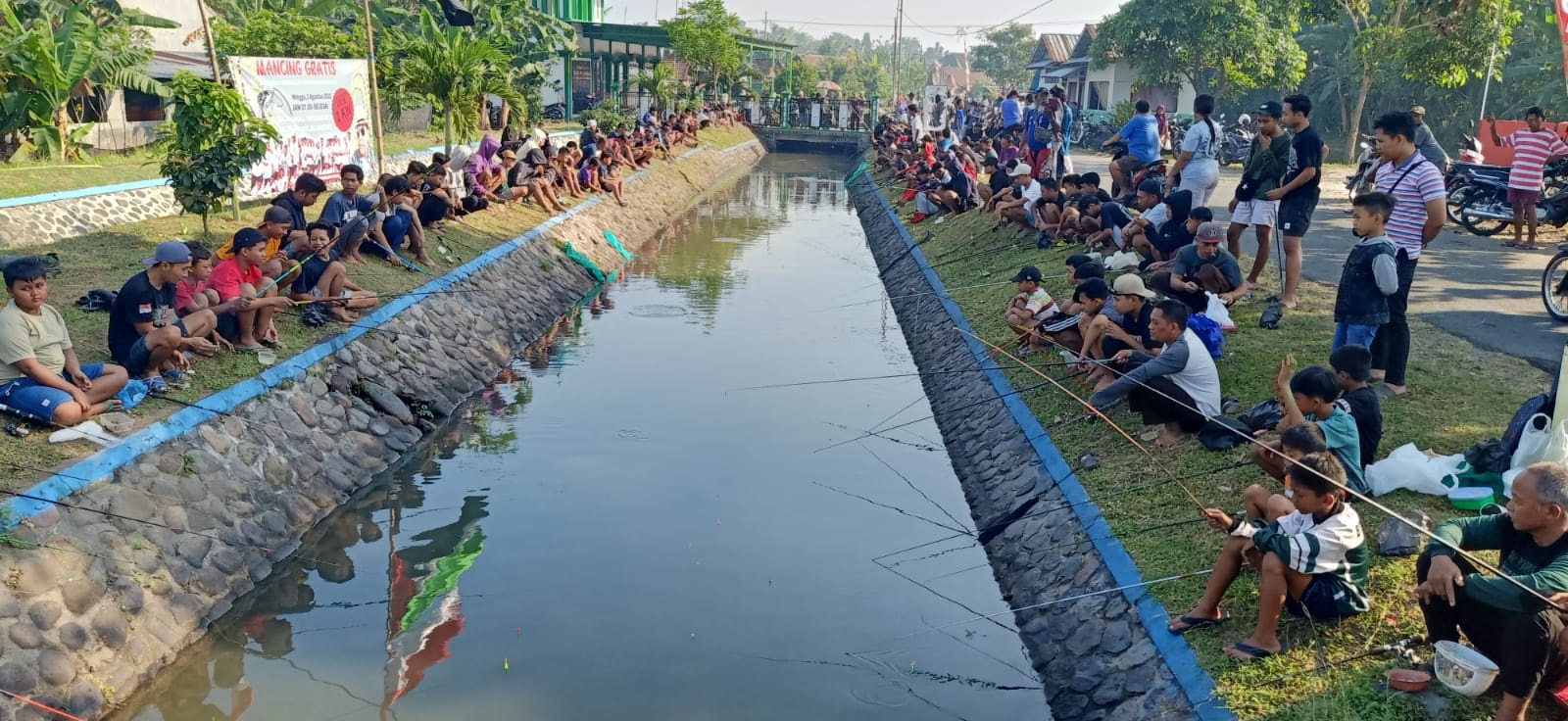 Masyarakat meramaikan acara mancing gratis yang diadakan oleh kartar Kecamatan Mojoagung di Dam Brantas Penanggalan, Desa Dukuhdimoro, Minggu (3/8).