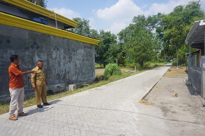 TUNJANG MOBILITAS WARGA: Kepala Desa Janti H Musta&rsquo;in didampingi perangkat desa saat meninjau lokasi pembangunan jalan paving di Dusun/Desa Janti, Jogoroto, Jombang.