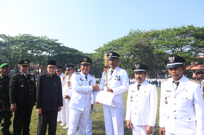 MENGABDI UNTUK MASYARAKAT: Kepala Desa Peterongan Ali Muzaki menerima piala penghargaan dari Camat Peterongan Mohammad Eryk Arif saat upacara peringatan HUT ke-80 Kemerdakaan RI, Minggu (17/8) pagi.