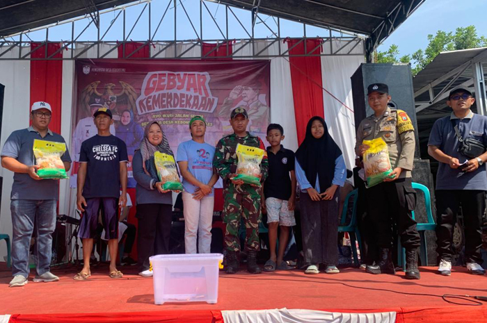 GEBYAR KEMERDEKAAN: Kepala Desa Kebontemu Sirojul Munir (paling kiri) memberikan apresiasi sembako kepada para pemenang undian jalan sehat Desa Kebontemu, Minggu (7/8) siang.