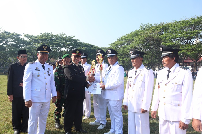CAPAIAN REALISASI PBB-P2 TERTINGGI: Kepala Desa Senden Agus Budianto menerima piala penghargaan saat upacara peringatan HUT Kemerdekaan RI ke-80, Minggu (17/8) pagi.