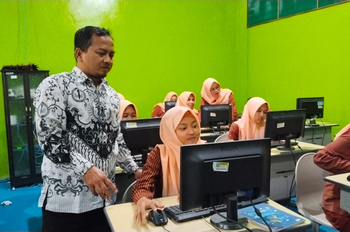 TELATEN: Guru membimbing siswa saat belajar di lab komputer SMAN Jogoroto, Jombang, (26/9).