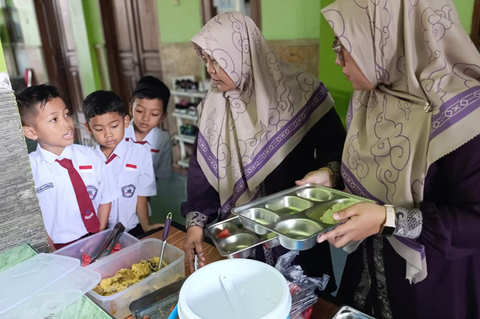 ANTUSIAS: Sejumlah guru SD Islam Roushon Fikr, Jombang saat mengambilkan menu makan di sekolah, (3/10).