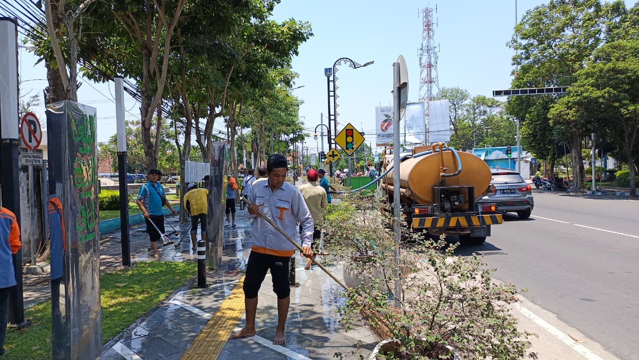 DIBERSIHKAN: Petugas melakukan pembersihan dan penyemprotan trotoar Jl KH Wahid Hasyim, Jombang Rabu (8/10).