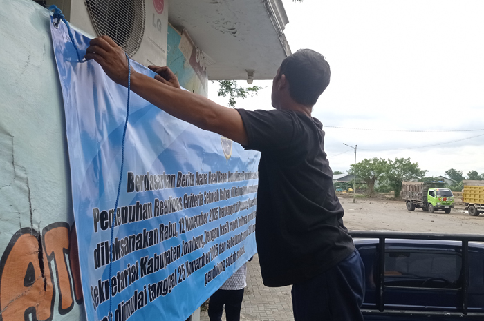 SEGERA DITUTUP: Petugas memasang banner di eks Terminal Barang Desa Tunggorono, Kecamatan Jombang.