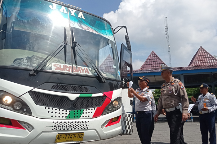 LAIK JALAN: Tedjo dan Ken Wahyu menempel stiker pada bus yang dinyatakan lolos pemeriksaan di Terminal Kepuhsari, Jombang, Kamis (11/12).