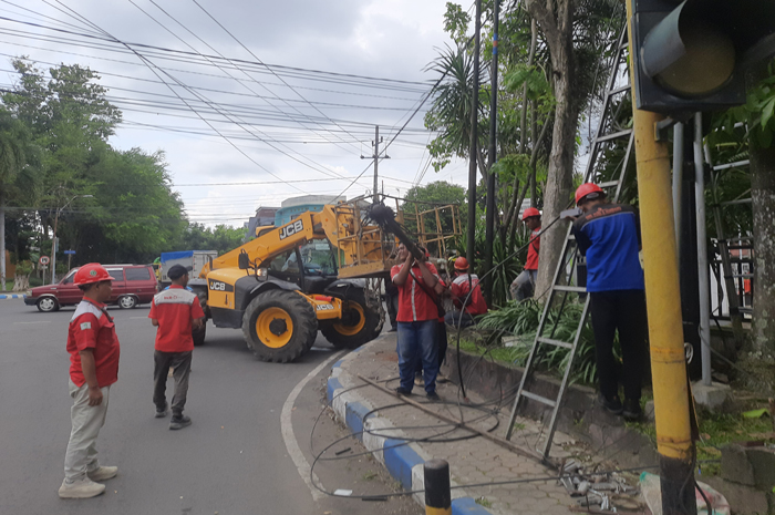 DIBONGKAR: Petugas Dinas PUPR saat membongkar tiang FO di Jalan Cak Durasim (11/12/2025). (Anggi Fridianto/Radar Jombang)