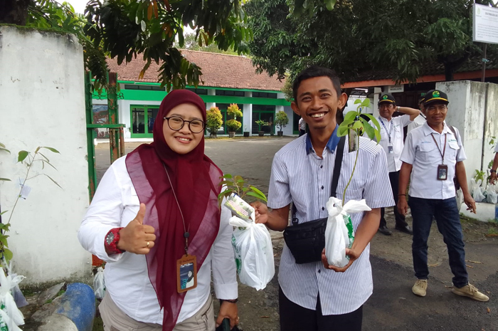 PEDULI LINGKUNGAN: Administratur/KKPH Jombang Enny Handhayany YS SHut bersama karyawan Perum Perhutani Jombang saat membagikan bibit pohon kepada pengguna jalan di sekitar kantor Perhutani Jombang.