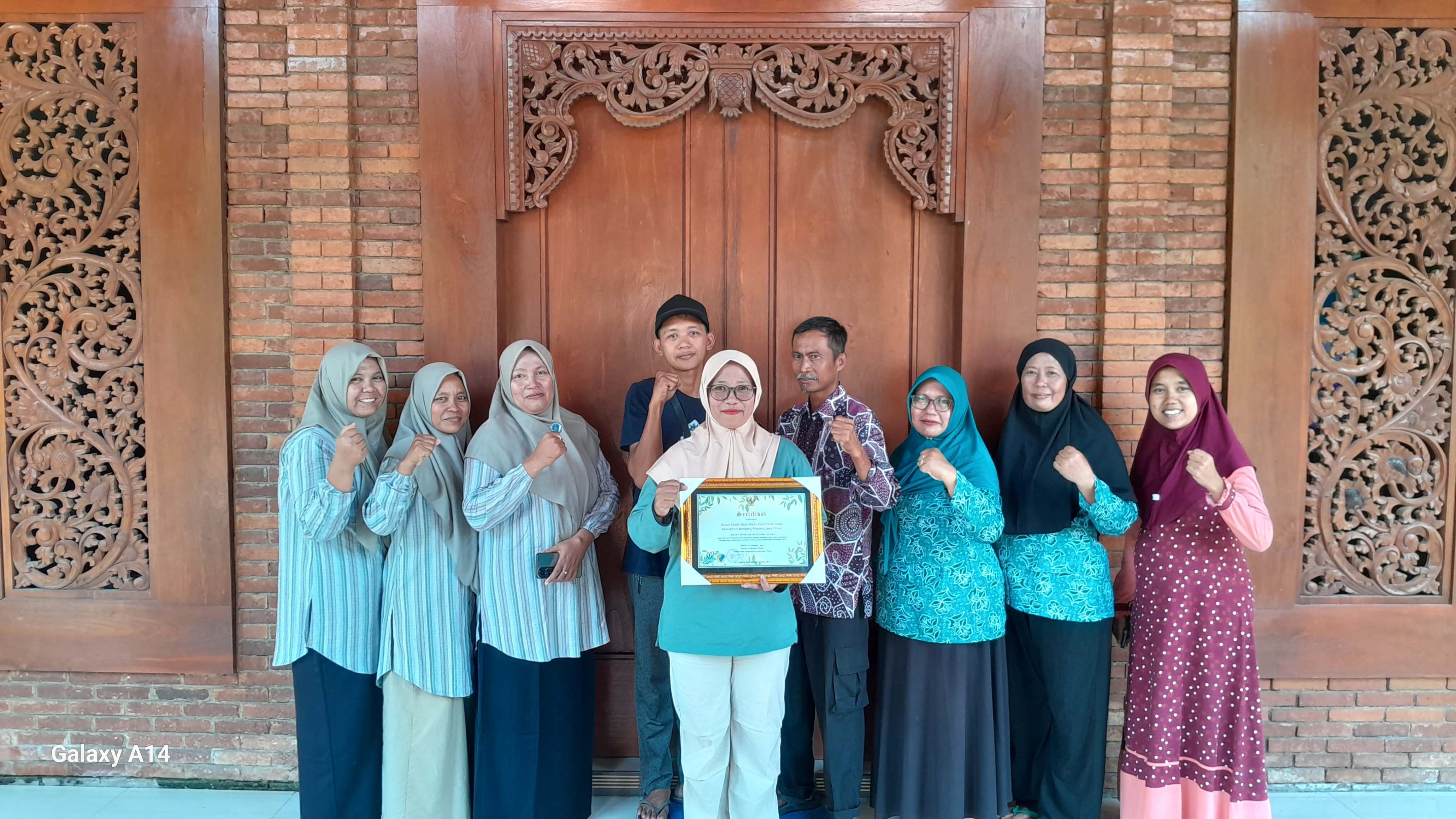 Kepala Desa Made Winarsih bersama jajaran perangkat desa menunjukkan sertifikat Proklim Utama 2025.