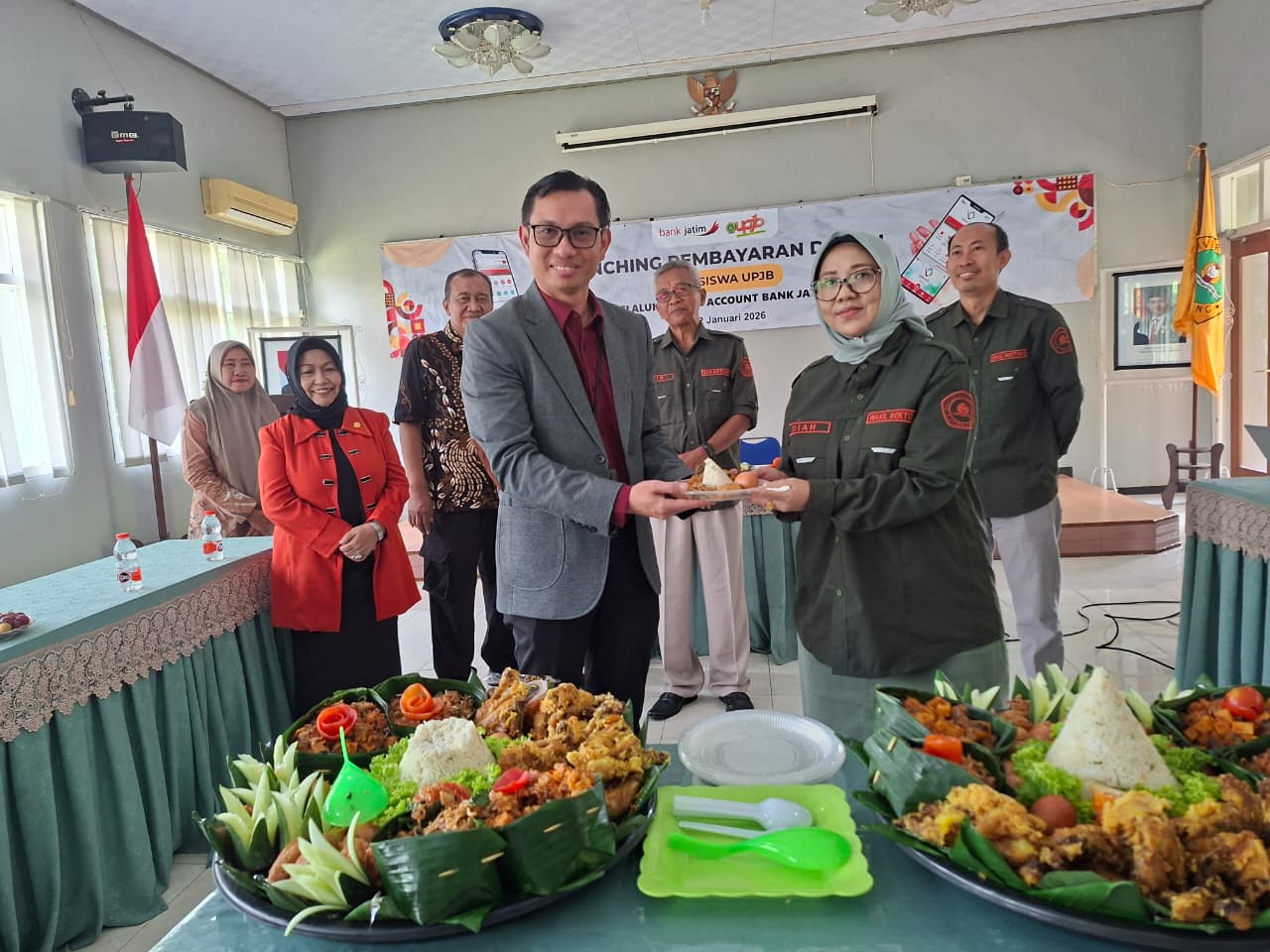 SINERGI: Pemimpin Bank Jatim Cabang Jombang Hanif Julhamsyah menyerahkan potongan tumpeng kepada Wakil Rektor II UPJB Dr. Diah Puji Nalibrata Msi.