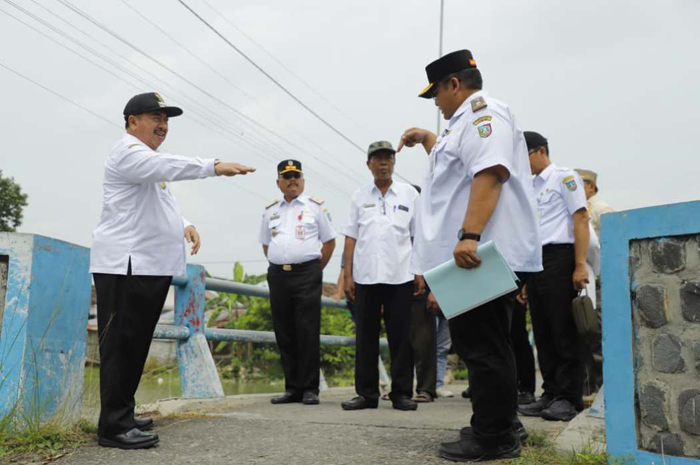 KEBUTUHAN MASYARAKAT: Kepala Desa Kudubanjar Gatot Kuswanto mendampingi kunjungan Bupati Jombang Warsubi bersama jajaran kepala OPD terkait saat meninjau jembatan darurat Desa Kudubanjar.