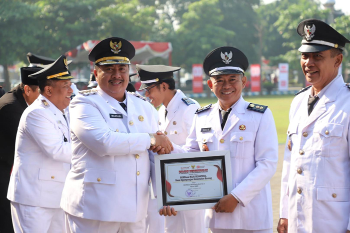 APRESIASI: Kepala Desa Ngampungan Rohan saat menerima piagam penghargaan dari Bupati Jombang Warsubi sebagai salah satu BUMDesa berkinerja baik 2025.