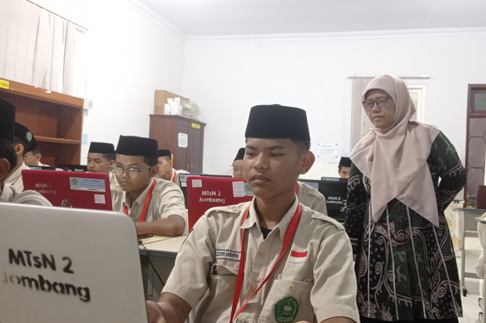 SERIUS: Kepala MTsN 2 Jombang, Agustin Aminah, memantau siswa mengerjakan tryout TKA di laboratorium komputer , Kamis (5/2).