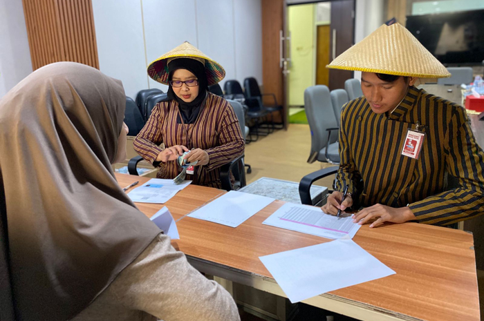 UNIK: Pegawai Bank Jatim Cabang Jombang mengenakan pakaian kebaya khas budaya Jawa saat melayani penukaran uang baru, Selasa (10/3). 