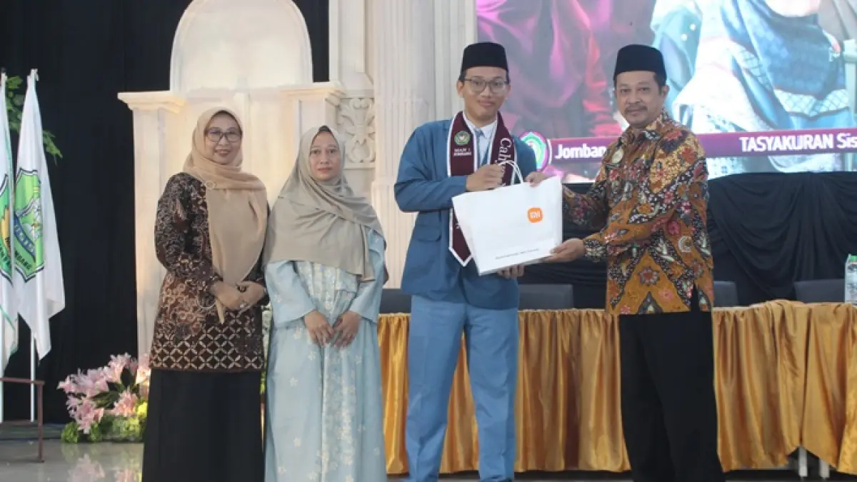 BERPRESTASI: Cahya Nugraha, finalis OSN Bidang Kebumian 2025 menerima hadiah yang diserahkan Kasubag TU Kemenag Jombang, Dr Arif Hidayatulloh. (Wenny Rosalina/Radar Jombang)