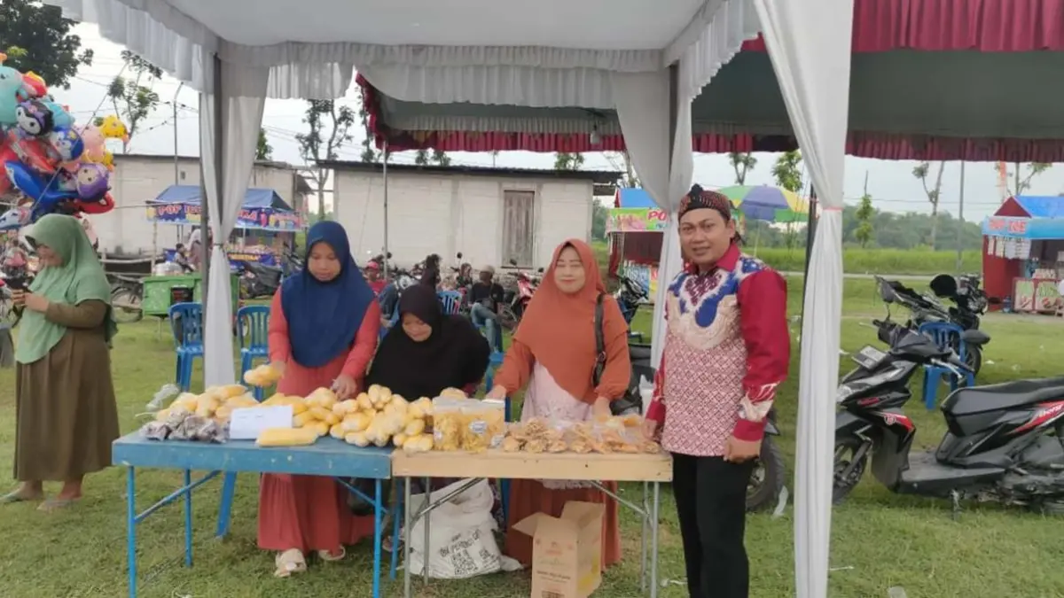 GENJOT EKONOMI LOKAL: Pj Kepala Desa Kampungbaru Daniel Danang Darmawan mengunjungi stan produk lokal desa saat kegiatan sedekah desa dan gelar potensi UMKM Desa Kampungbaru, Plandaan, Jombang, Jumat (8/5) sore. (Dwi Aris/Radar Jombang)