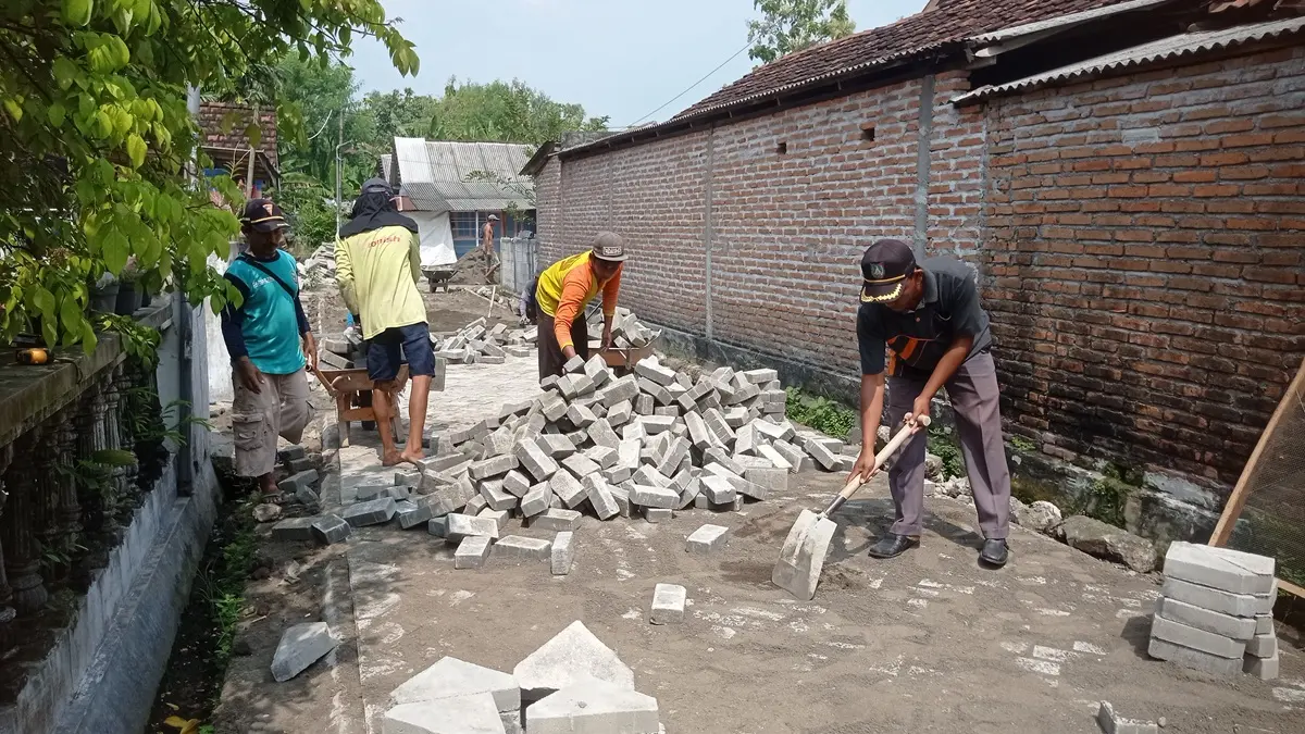 DIKEBUT: Perangkat desa dan TPK Desa Jatilmerek, Plandaan, Jombang memantau pembangunan jalan paving program Desa Mantra di Dusun Keputran. (Ainul Hafidz/Radar Jombang)