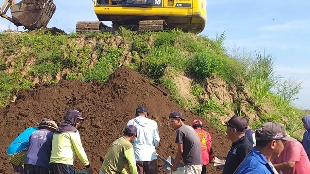 GOTONG ROYONG: Warga dan petani mengisi material jumbo bag di Desa Sudimoro, Kecamatan Megaluh, Jombang persiapan penanganan sementara pintu enam Dam Karet Jatimlerek yang jebol. (Ainul Hafidz/Radar Jombang)
