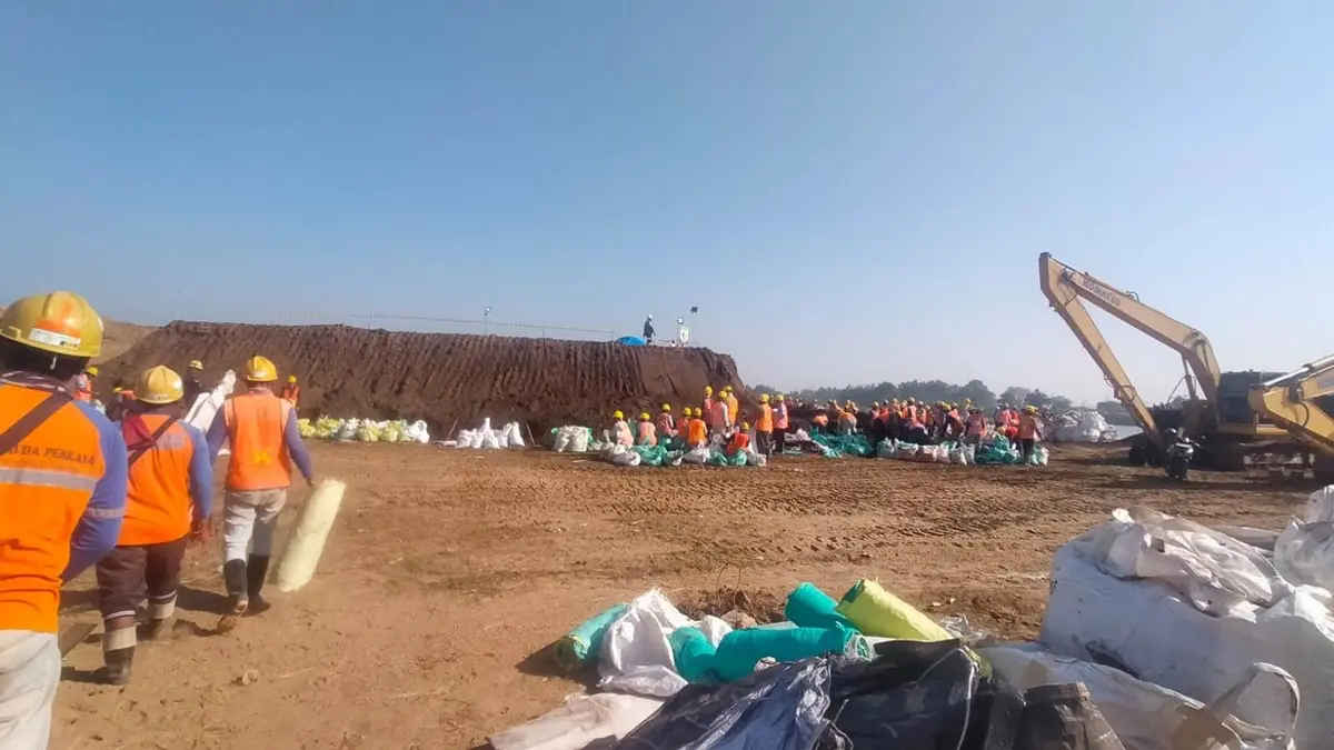 GOTONG ROYONG: Warga bersama petani utara Brantas memasukkan material sand bag dan jumbo bag di sisi Desa Sudimoro, Kecamatan Megaluh, Jombang untuk penanganan pintu enam Dam Karet Jatimlerek yang rusak. (Ainul Hafidz/Radar Jombang)