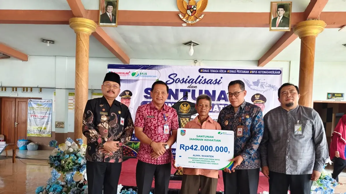 Kepala Dinas Tenaga Kerja (Disnaker) Jombang Isawan Nanang Risdiyanto bersama Sekdakab Jombang Agus Purnomo menyerahkan santunan kematian kepada ahli waris petani tembakau di Balai Desa Karangpakis, Kecamatan Kabuh, Kamis (25/6). (Achmad RW/Radar Jombang)