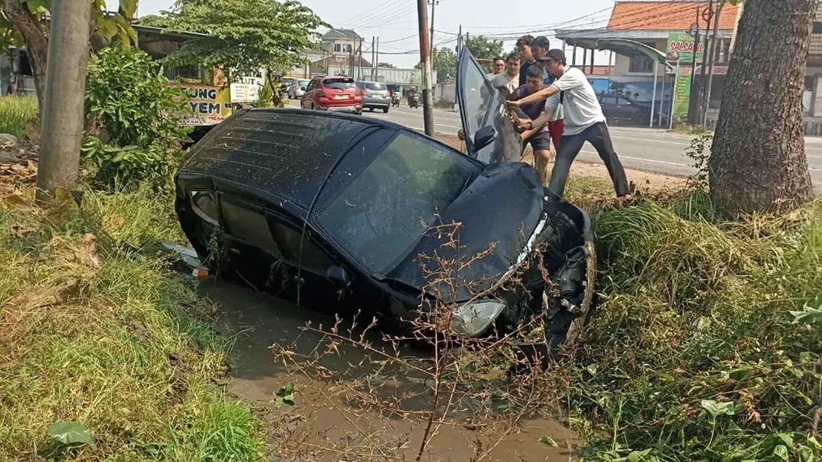 Sebuah Toyota Avanza terperosok ke parit di jalur arteri Desa Gondangmanis, Kecamatan Bandarkedungmulyo, Jombang Sabtu (4/7) siang. (Achmad RW/Radar Jombang)