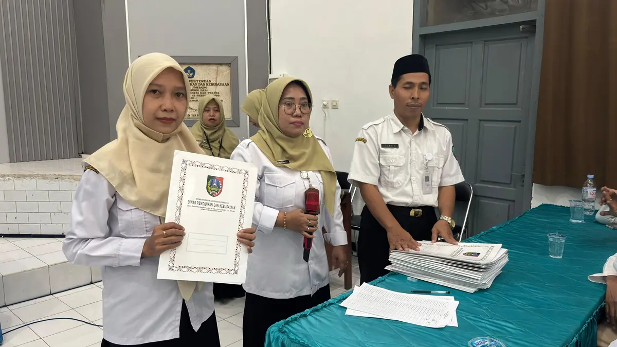 SIMBOLIS: Salah satu guru yang dimutasi menerima SK di Aula 1 Dinas Pendidikan dan Kebudayaan Kabupaten Jombang, Rabu (8/7). (Wenny Rosalina/Radar Jombang)
