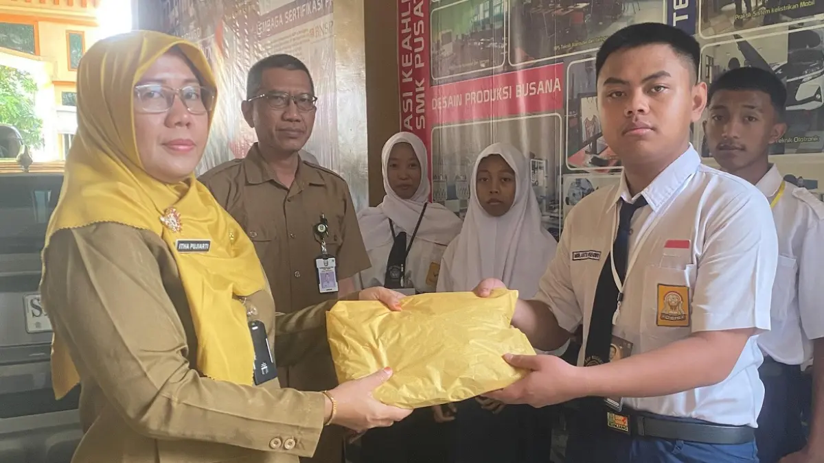 Kepala SMKN Gudo, Itha Itha Pujiarti SS MPd, memberikan seragam gratis kepada siswa baru, Senin (13/7).