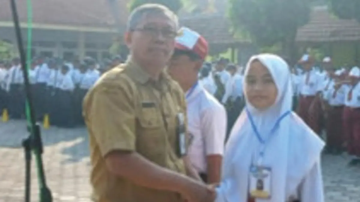 INOVATIF: Kepala SMPN 2 Mojowarno, Jombang, Muji Suwanto SPd, menyematkan identitas peserta kepada perwakilan murid baru saat pembukaan, Senin (13/7) pagi.&nbsp;(Dwi Aris/Radar Jombang)