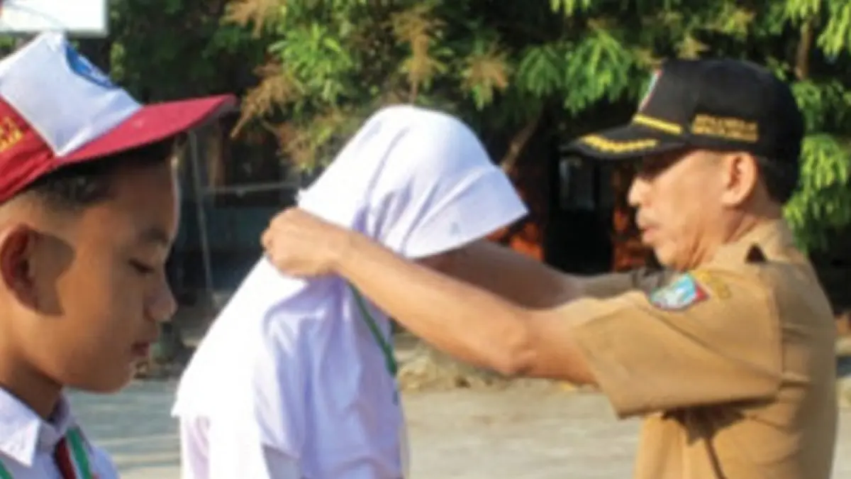 MEMBANGGAKAN: Kepala SMPN 2 Plandaan, Jombang, Drs Bambang Setiyawan MEd, menyematkan id card kepada perwakilan murid baru saat pembukaan MPLS, Senin (13/7) pagi.&nbsp;(Dwi Aris/Radar Jombang)