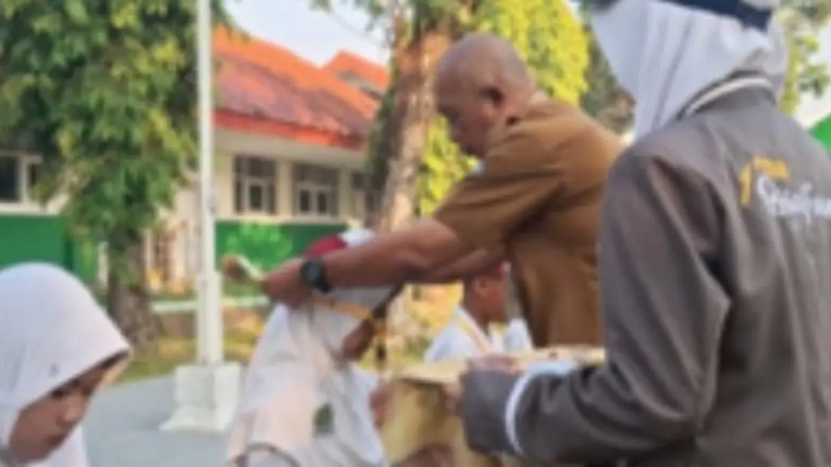 RAMAH: Kepala SMPN 4 Jombang, Slamet Agus Tri Prastyo SPd, mengalungkan id card kepada perwakilan murid baru saat upacara pembukaan MPLS Senin (13/7) pagi.&nbsp;(Dwi Aris/Radar Jombang)