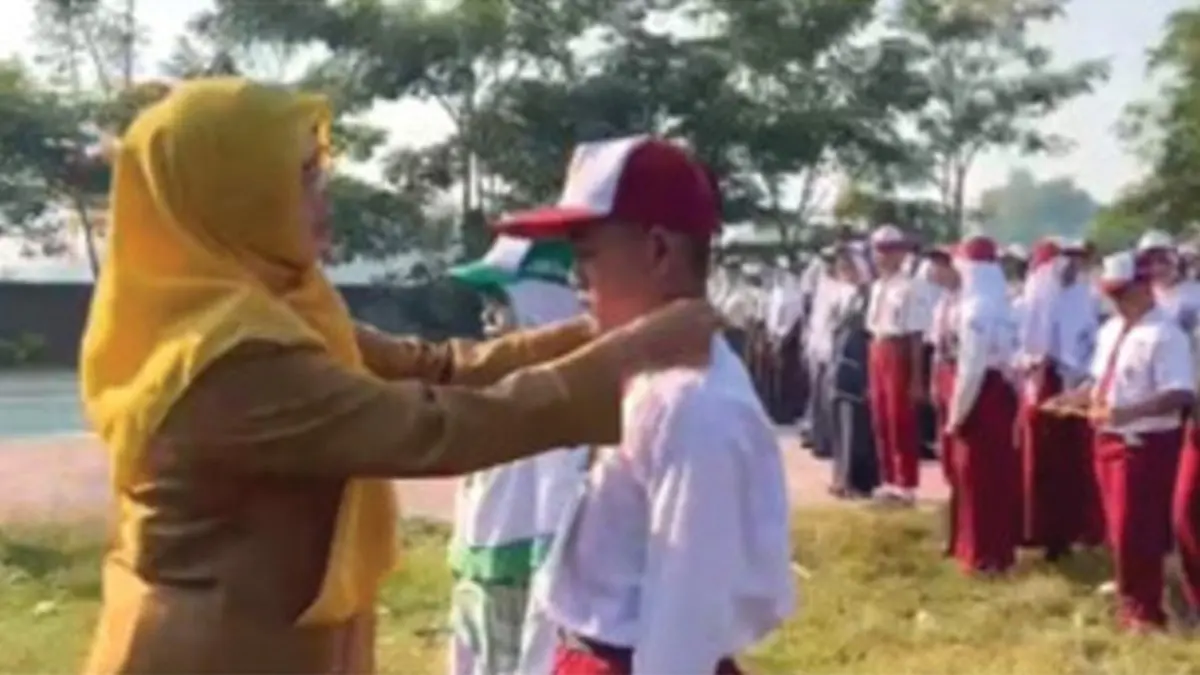 SIMBOLIS: Kepala SMPN 1 Kudu, Jombang, Srimudayani Dewi Astutik MPd, mengalungkan identitas kepada perwakilan peserta MPLS di SMPN 1 Kudu, Senin (13/7) pagi.&nbsp;(Dwi Aris/Radar Jombang)